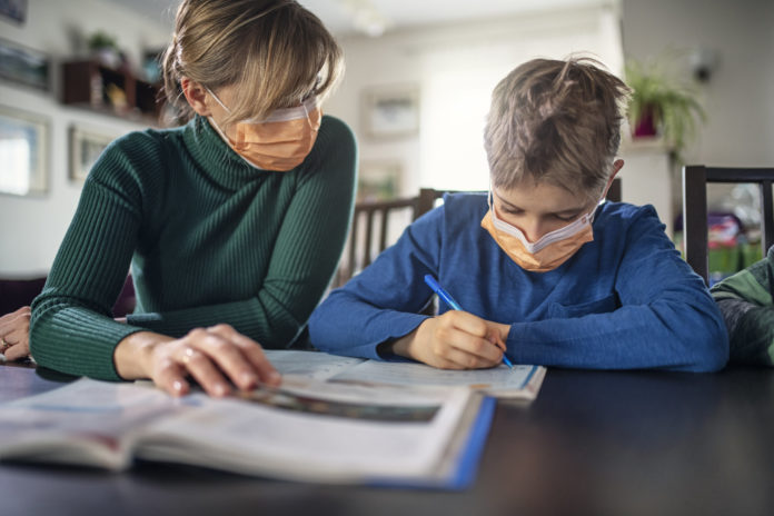 Mother homeschooling her son wearing face masks